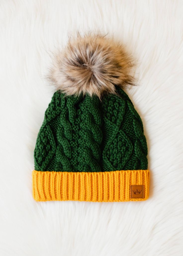 a green and yellow hat with a fur pom