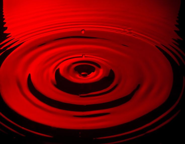 red water ripples into the dark, circular shape on top of each other in a pond