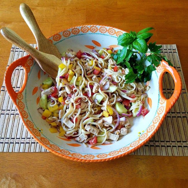 an orange and white bowl filled with food on top of a wooden table next to a spoon