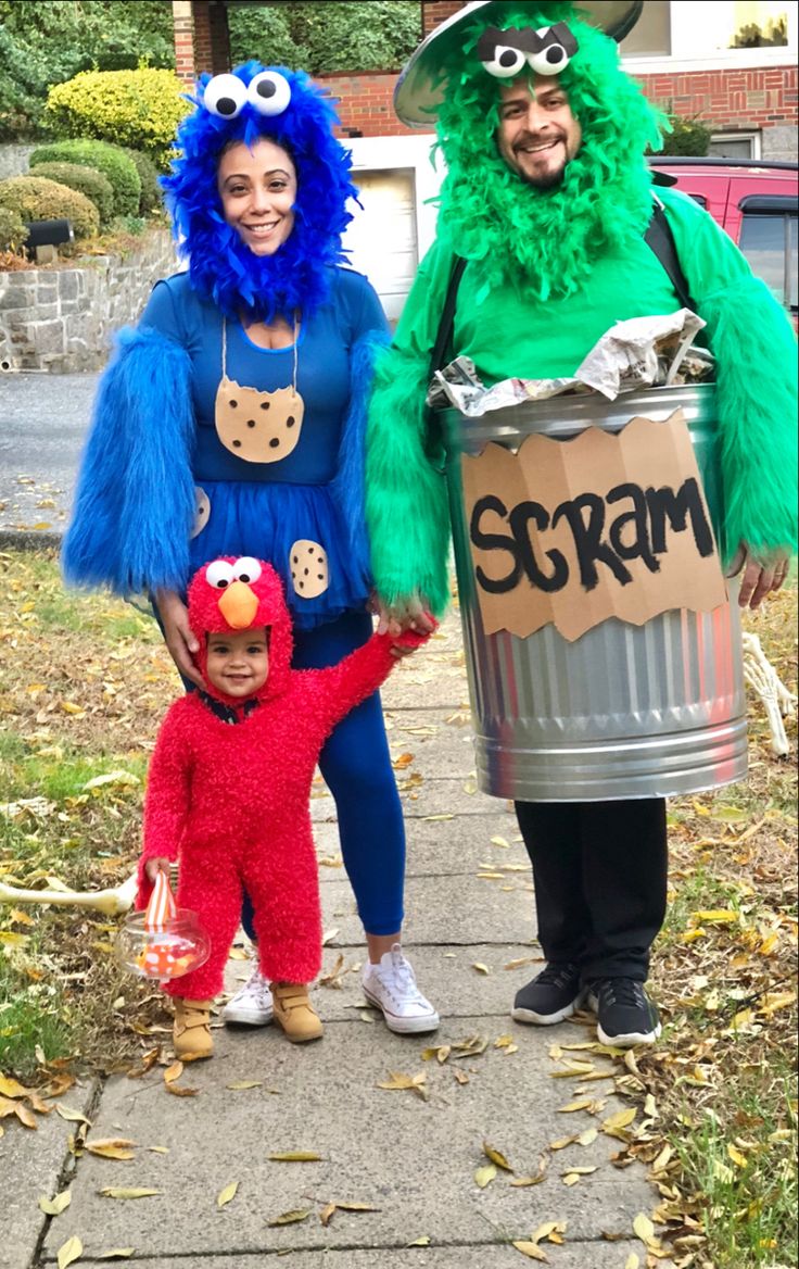 two people in costumes standing next to a child dressed as sesame and the cookie monster