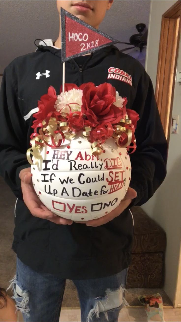 a person holding a cake with red flowers on it