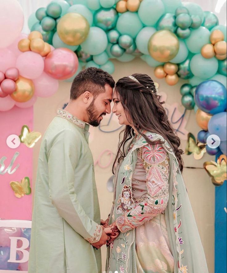 a man and woman standing next to each other in front of balloons