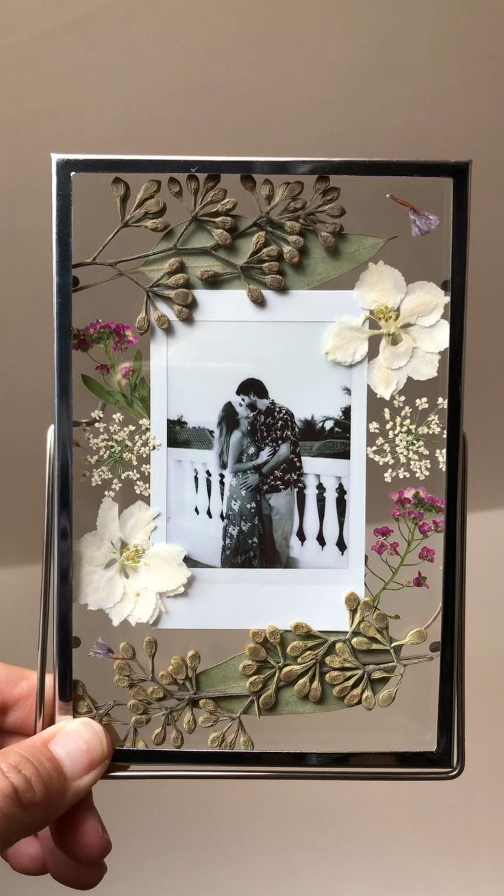 a person holding up an altered photo with flowers and leaves on the inside of it