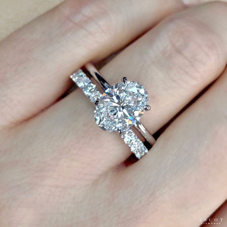 a woman's hand with a diamond ring on top of her finger and an engagement band