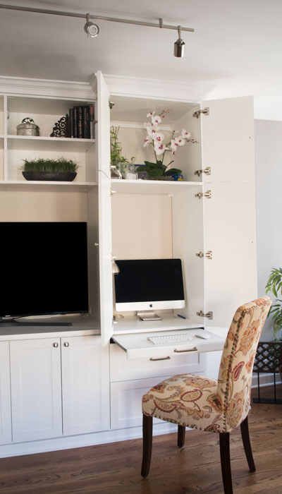 a computer desk with a monitor and keyboard on top of it in front of a white bookcase