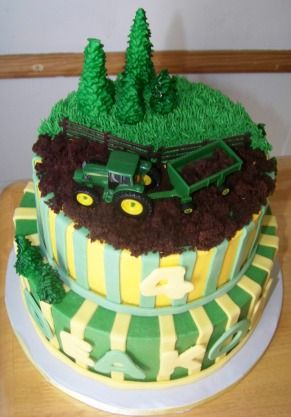 there is a green and yellow cake that has tractors on the top, trees in the background