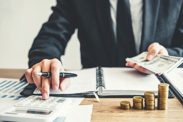 a man sitting at a desk with stacks of money and calculator