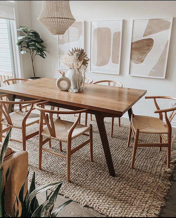 a dining room table with chairs and pictures on the wall behind it in front of a potted plant