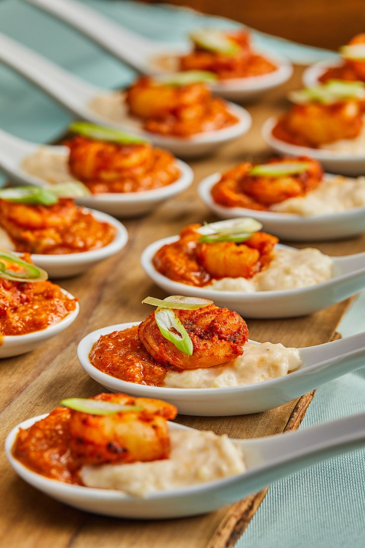 small white bowls filled with food on top of a wooden table