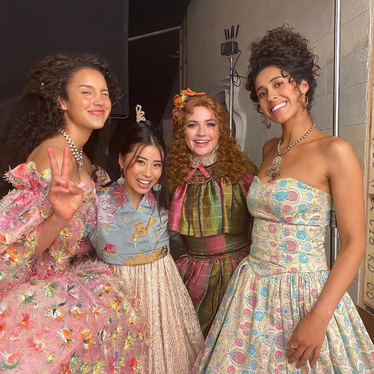 three women in dresses standing next to each other with one woman making the peace sign