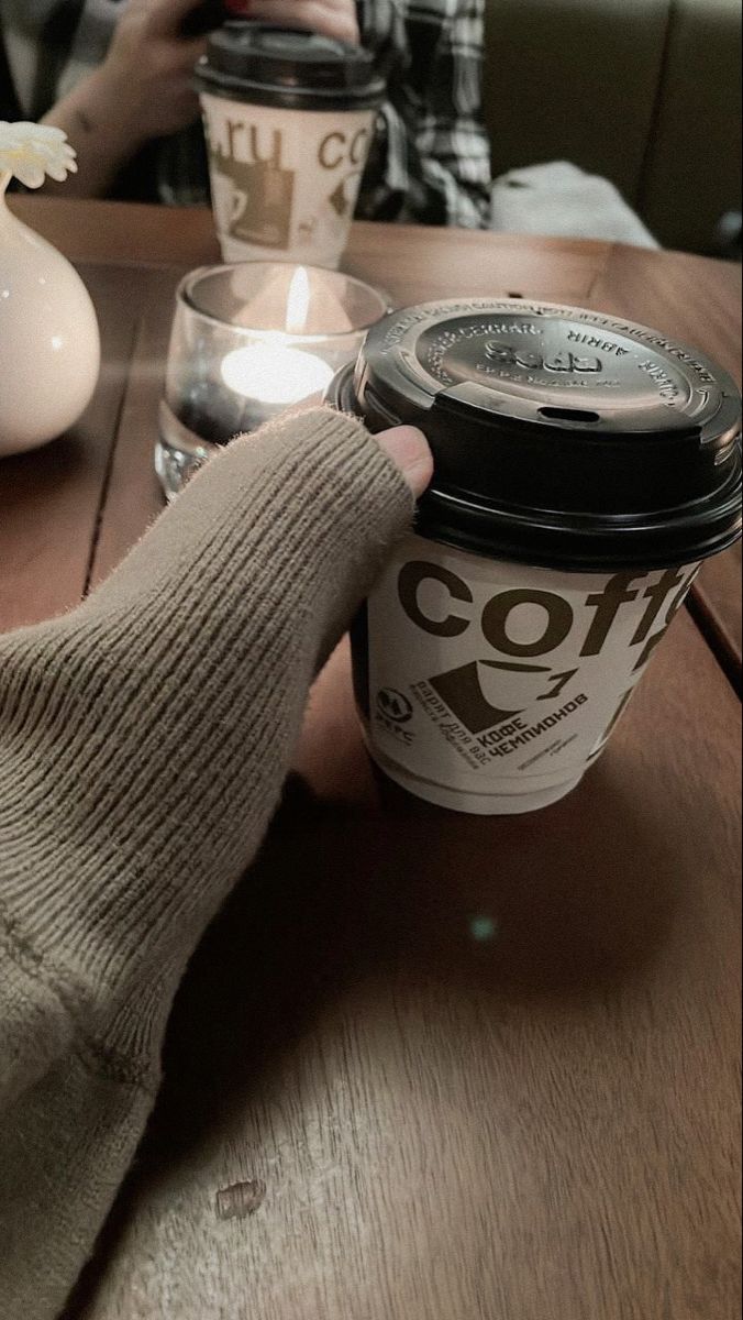 a person holding a coffee cup on top of a wooden table