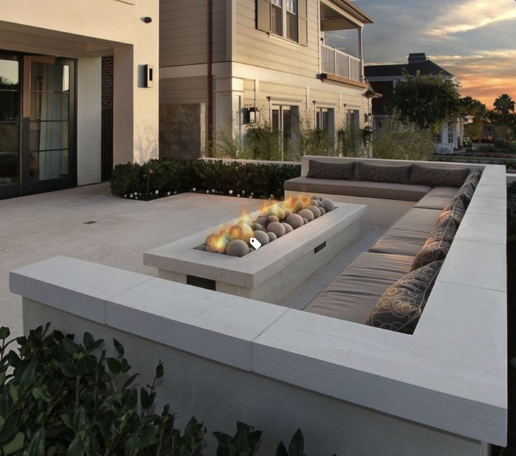 a fire pit sitting on top of a cement slab next to a house at sunset