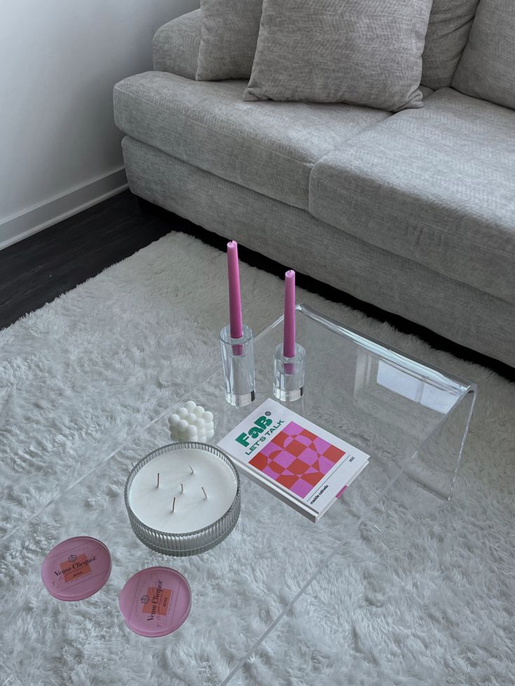 a living room area with a couch, coffee table and candles on the floor in front of it