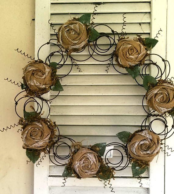 a wreath made out of wire and flowers on a window sill with shutters