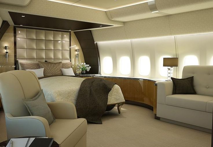 the interior of an airplane cabin with a bed and two armchairs in front of it