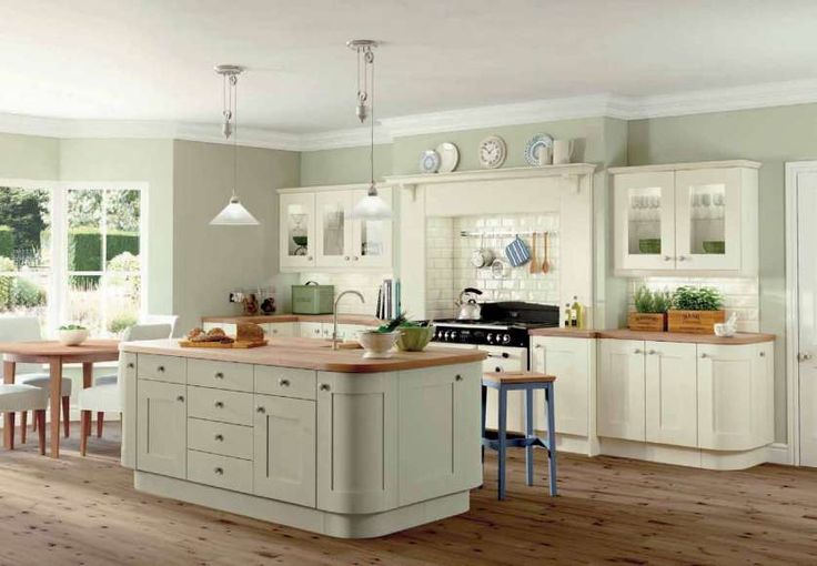 a large kitchen with white cabinets and wooden flooring is pictured in this image, there are two stools at the center of the island