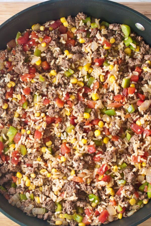 a pan filled with rice and vegetables on top of a wooden table