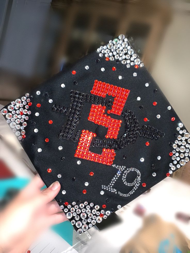 a black graduation cap with red and white sequins