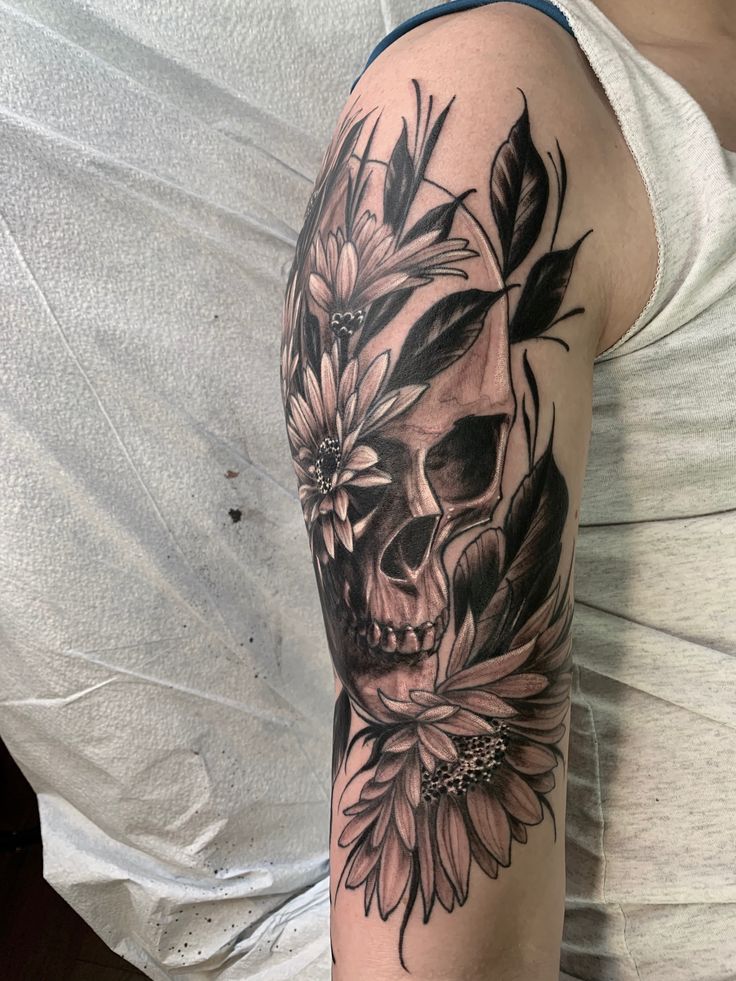 a woman with a skull and flowers tattoo on her arm