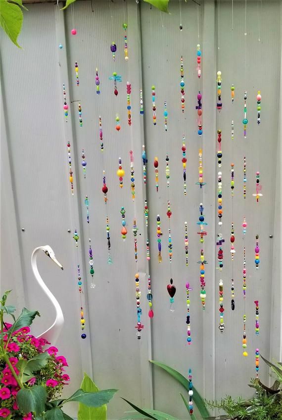 a white swan standing in front of a wall with beads hanging from it's sides