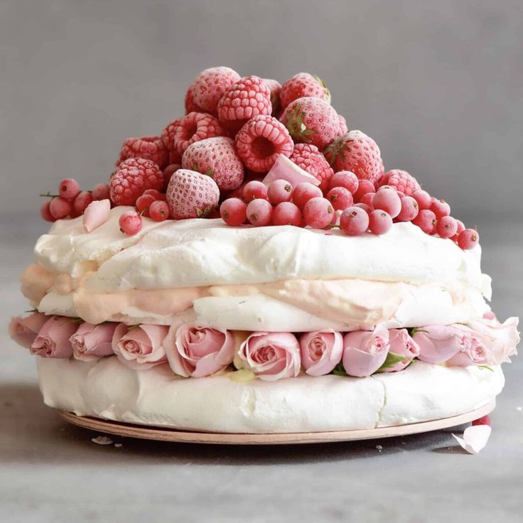 a cake with raspberries and flowers on top is shown in front of a gray background