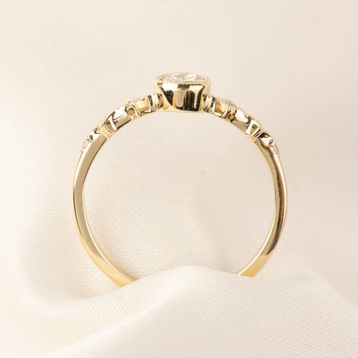 a yellow gold ring with three stones on the top and bottom, sitting on a white cloth