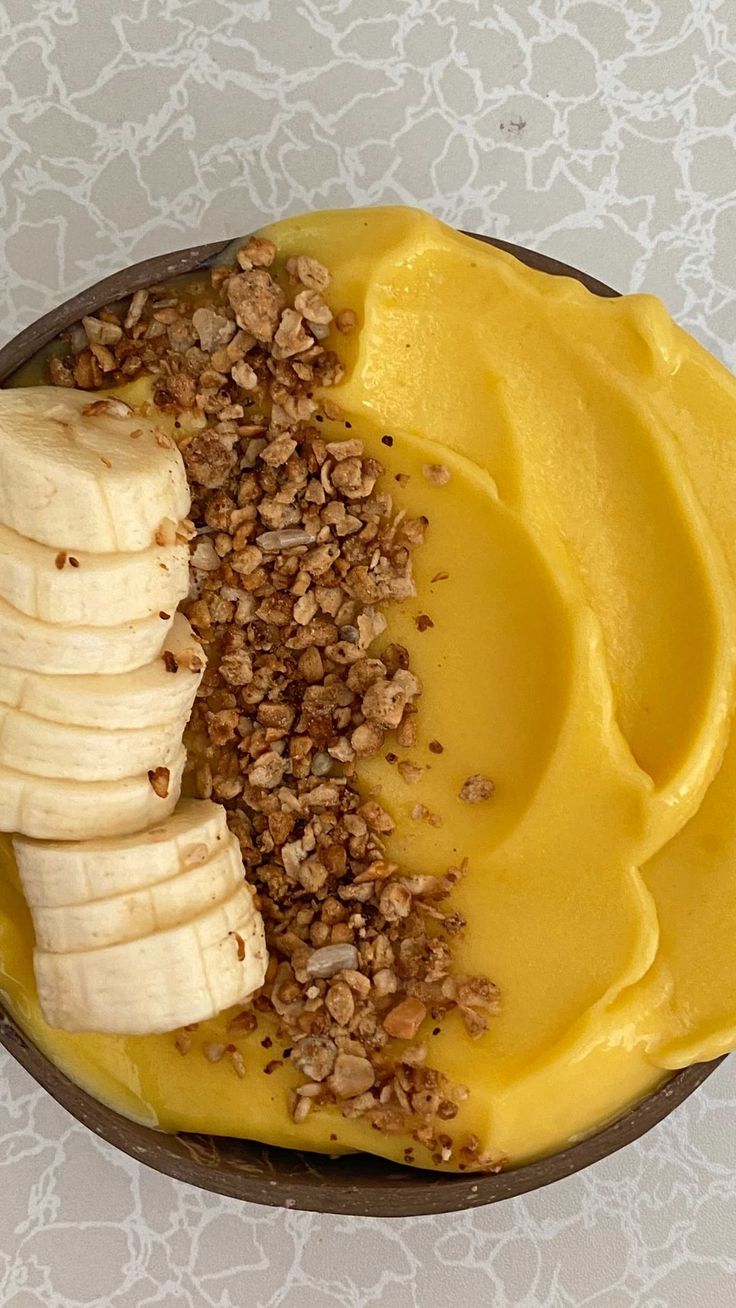 a bowl filled with bananas and granola on top of a table