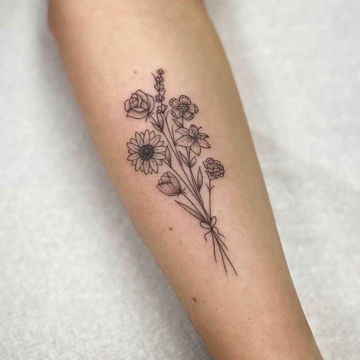 a woman's arm with flowers on it and the word love written in black ink