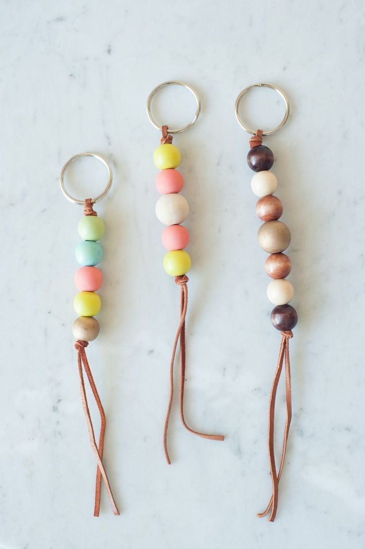 three key chains with different colored beads hanging from them on a white counter top next to each other