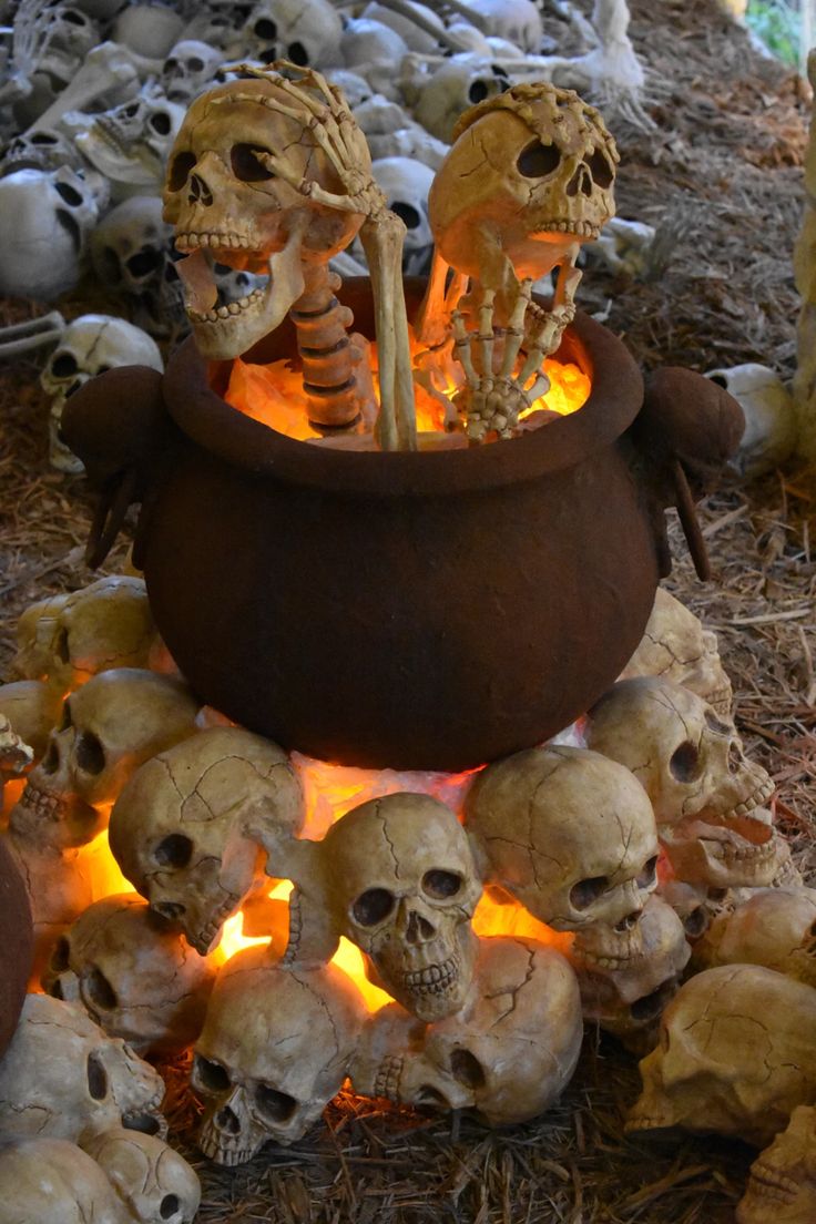 there are many skulls in the pot on the ground with fire coming out of it