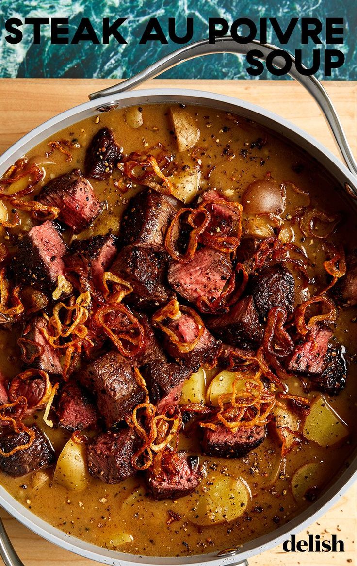 a pot filled with meat and vegetables on top of a wooden table