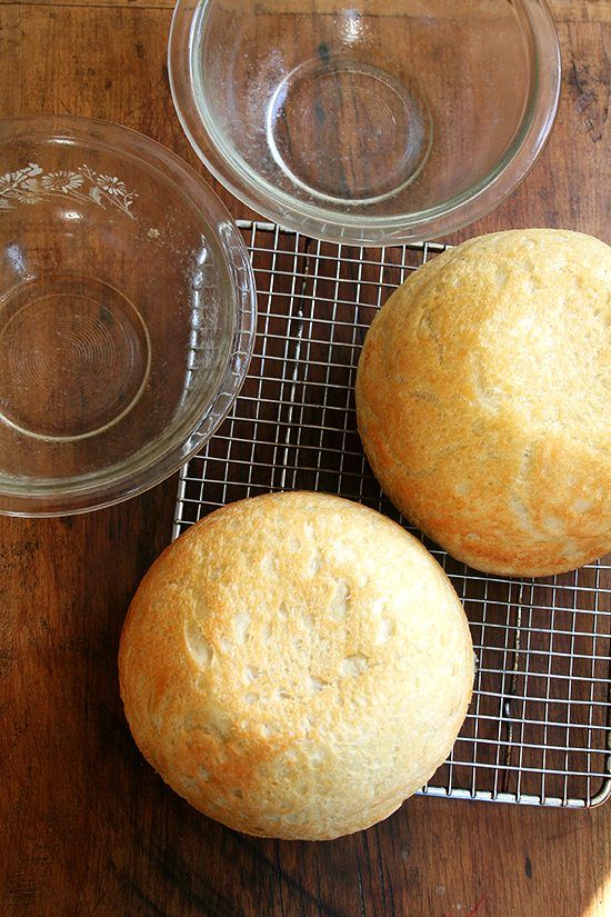 two muffins sitting on top of a cooling rack next to a glass bowl