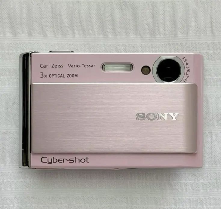 a pink camera sitting on top of a white sheet