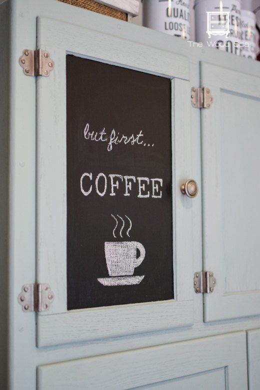 a chalkboard on the side of a cabinet with coffee written on it and two cups