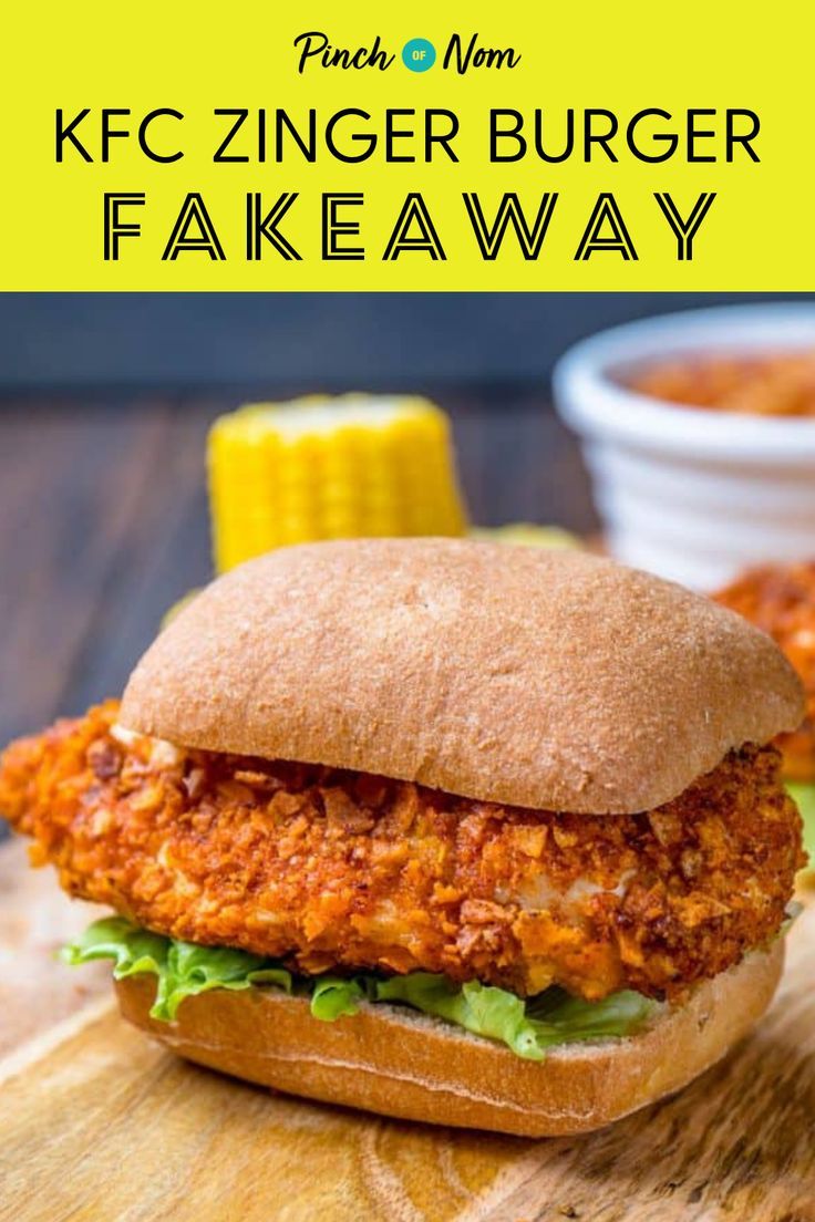 a chicken burger on a wooden cutting board with corn in the background and text overlay that reads, kfc zinger burger fakeaway