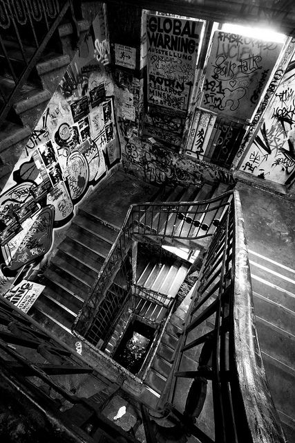 black and white photograph of stairs in an abandoned building with graffiti all over the walls