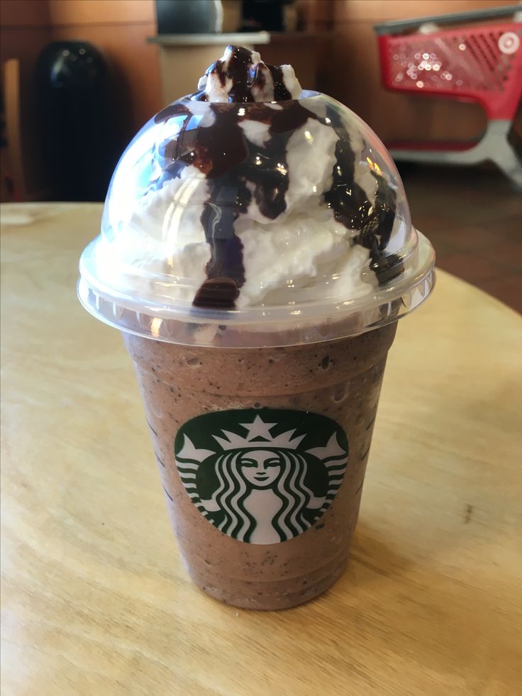 a starbucks drink with whipped cream and chocolate syrup on top is sitting on a table