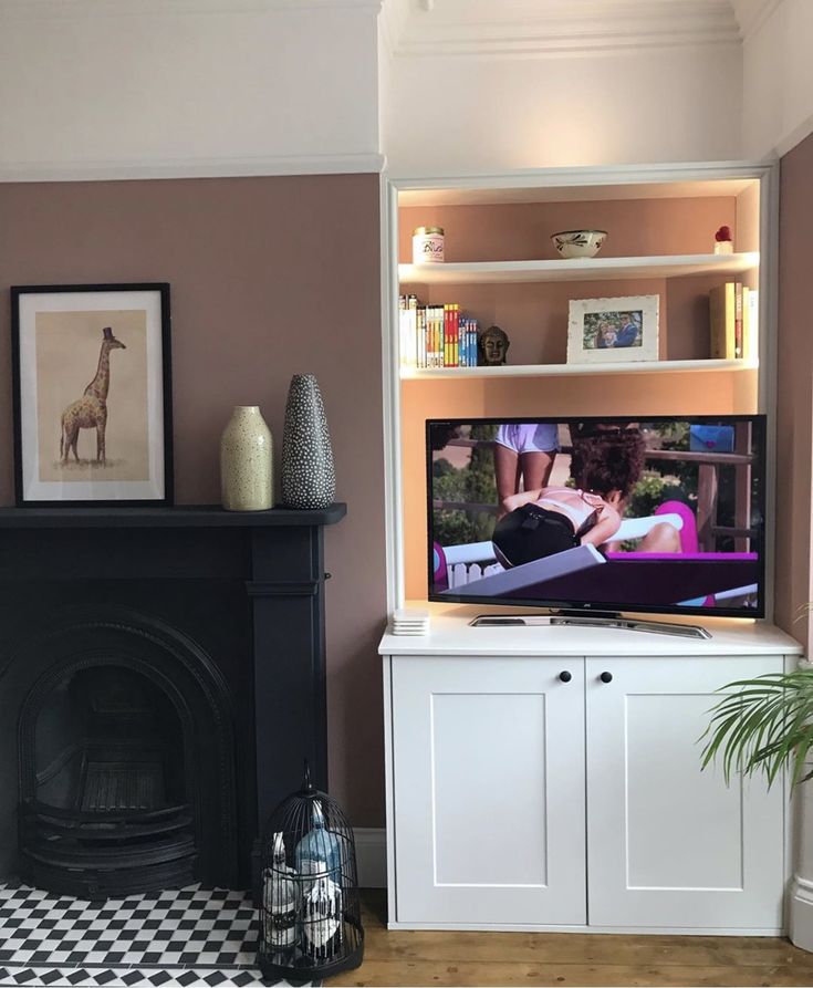 a flat screen tv sitting on top of a white entertainment center next to a fireplace