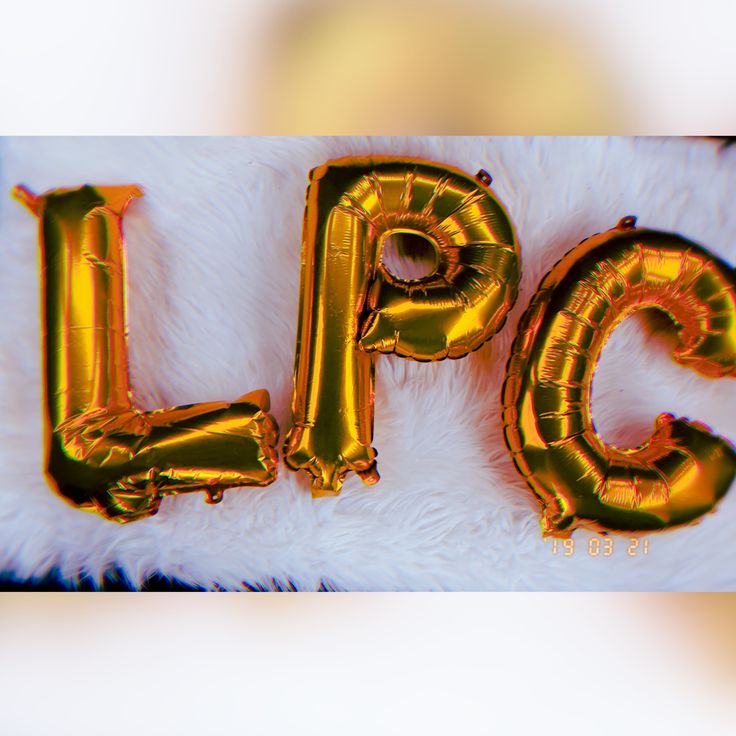 gold foil balloons spell out the word flick on a white fluffy surface with an animal's fur