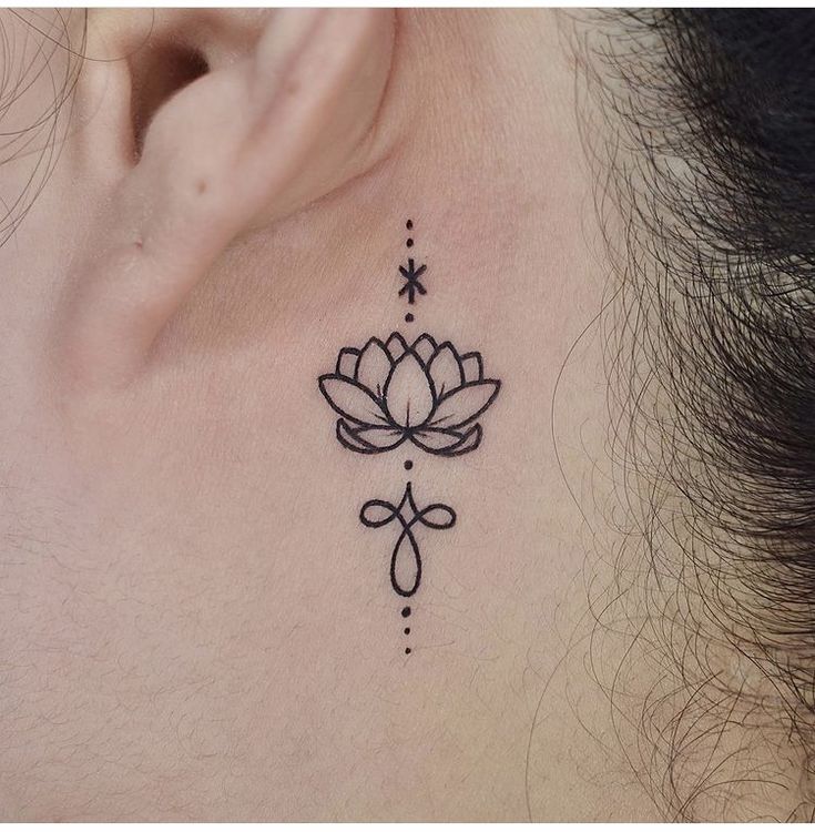 a close up of a person's ear with a flower tattoo on the side