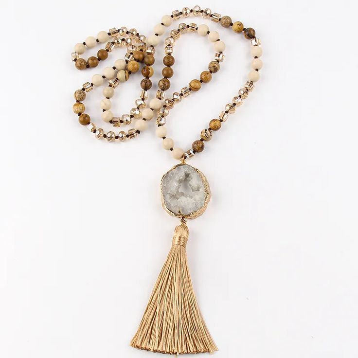 Bring a sophisticated Boho Chic touch to your summer outfit with our Precious Stone Boho Chic Beaded Necklace. A true embodiment of spiritual elegance, harmony and Bohème chic. Immerse yourself in sophistication with this elegant beaded necklace boasting a truly distinctive design. The pendant, created from a raw stone sample, is adorned with a delicate golden rim and a gracefully cascading tassel in a matching hue. Intricately beaded semi-precious stones are woven together to form this stunning Elegant Adjustable Tassel Necklace For Beach, Beige Beaded Necklace With Gold Round Beads, Spiritual Beaded Long Necklace For Gift, Spiritual Beaded Tassel Necklace For Beach, Elegant Beaded Chain Necklace For Summer, Elegant Summer Beaded Chain Necklace, Elegant Long Beaded Necklace For Beach, Beige Beaded Chain Necklace With Round Beads, Beaded Tassel Necklace With Round Beads For Beach