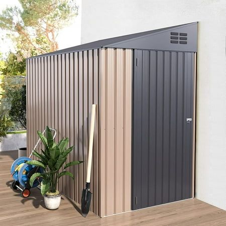 there is a potted plant next to a small metal shed with a broom on it