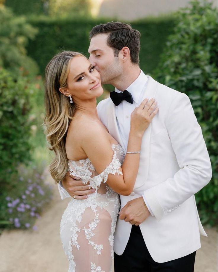 a man in a tuxedo and a woman in a dress are kissing each other