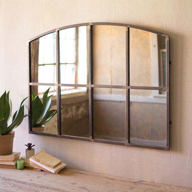 a mirror that is on the side of a wall next to a potted plant