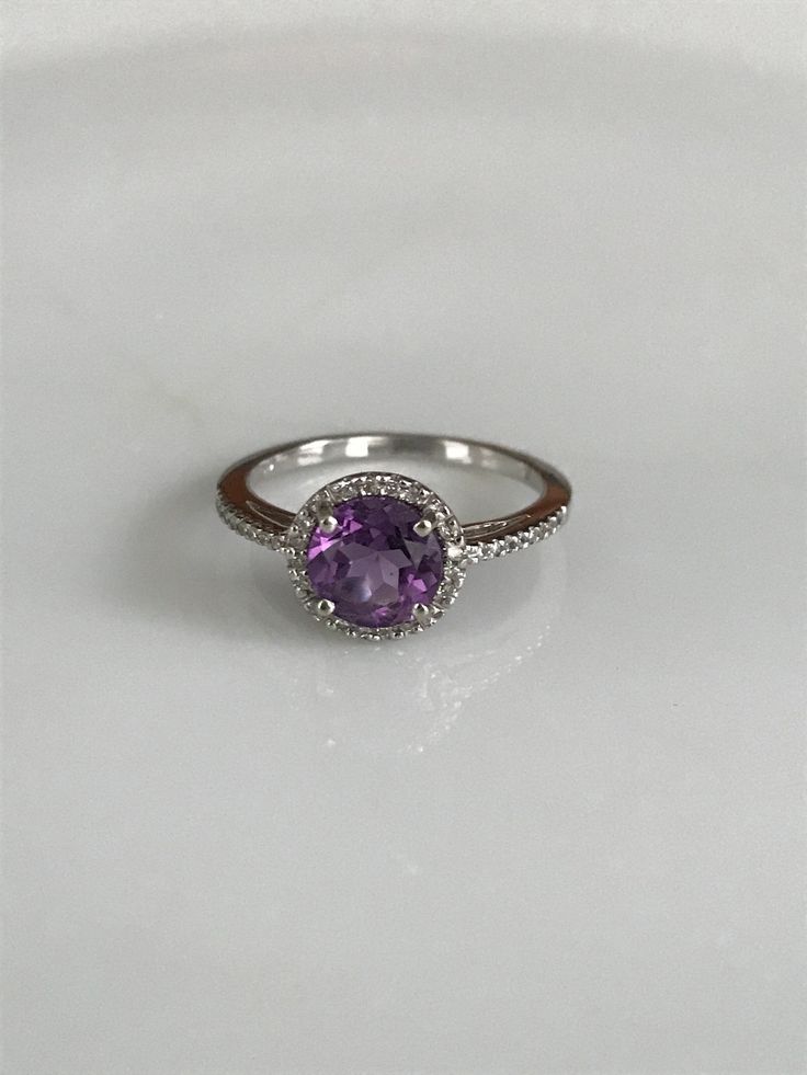 "This lovely halo ring features one round amethyst surrounded by tiny round diamonds that extend to about 1/4\" along the band on either side. The delicate purple shine of the amethyst and the twinkle of the diamonds make this ring simply dreamy! It is marked 14K, is a size 6 1/2 and is in beautiful condition. Please see all photos for details. Thank you for looking! I'm happy to offer layaway on certain items. Please ask for details." Elegant Purple Amethyst Ring With Round Band, Elegant Lavender Amethyst Ring, Classic Purple Diamond Ring With Halo Setting, Classic Purple Diamond Ring With Accent Stones, Classic Purple Amethyst Ring With Round Cut, Classic Purple Amethyst Ring Round Cut, Classic Purple Amethyst Round Cut Ring, Classic Purple Jewelry With Halo Setting, Formal Lavender Rings With Halo Setting