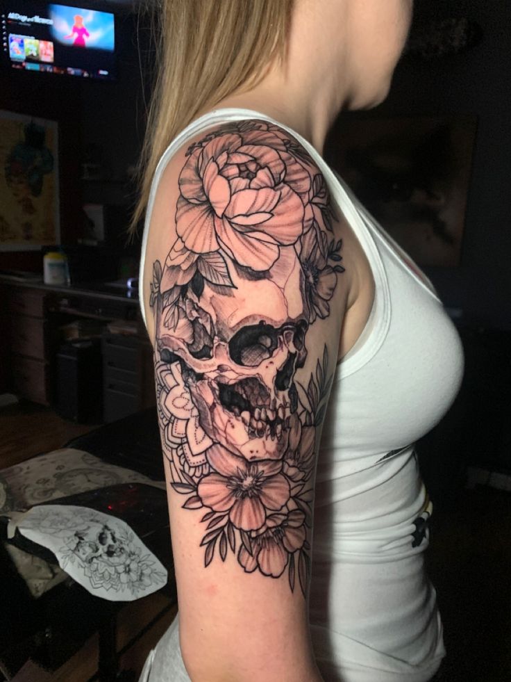 a woman with a skull and flowers tattoo on her arm