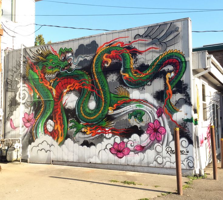 a large mural on the side of a building with dragon and flowers painted on it