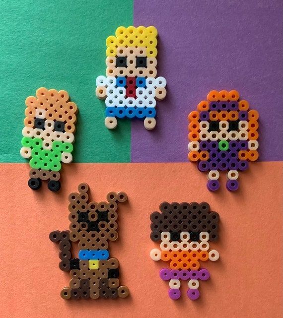 four different types of perler bead designs on colored paper with one being a dog