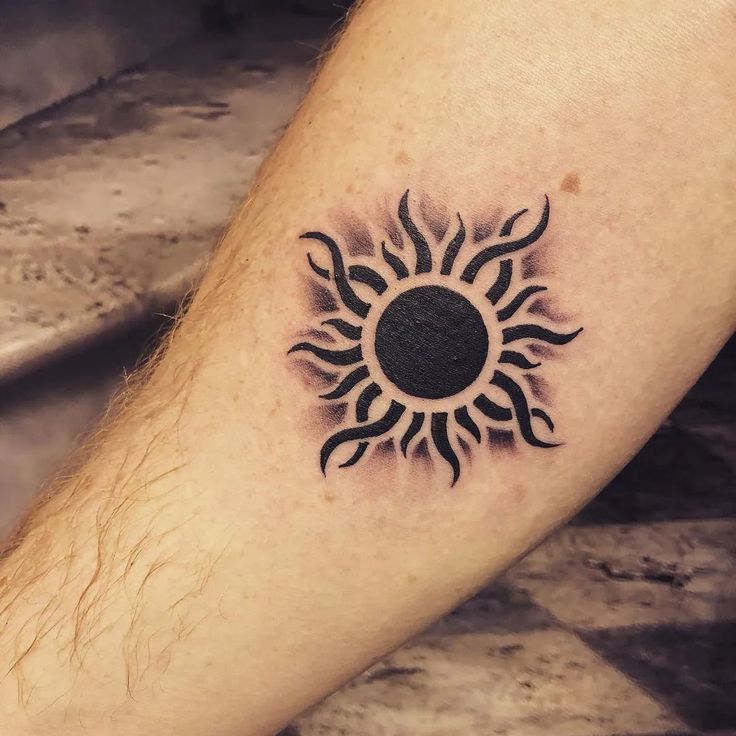 a black and white tattoo on the leg of a man with a sun in it