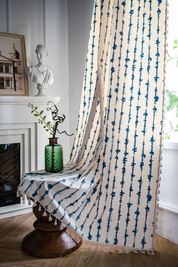 a curtain with blue and white tie - dye on it in front of a fireplace